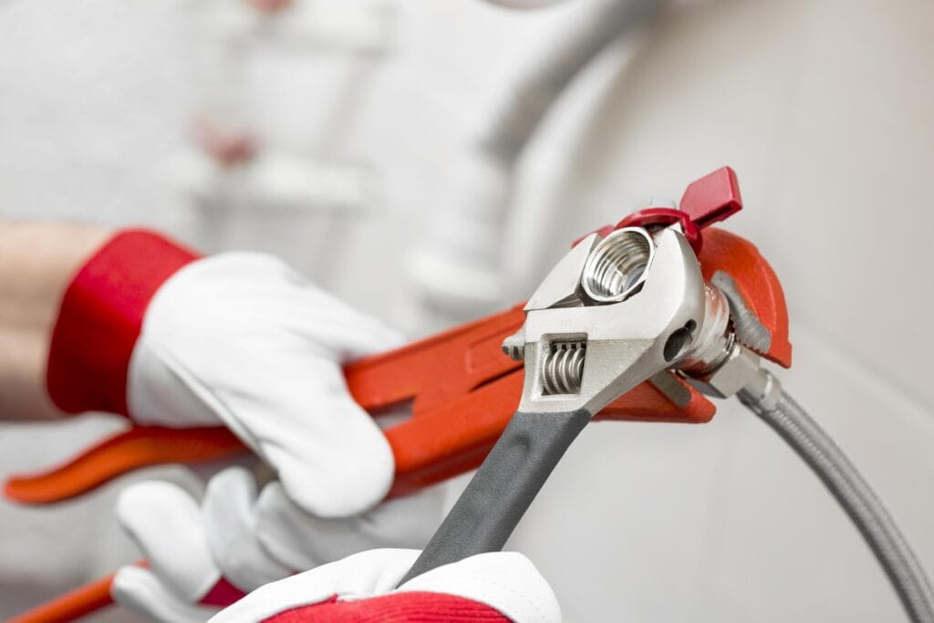 Plumber holding pipe wrenches for an emergency repair in West Jordan