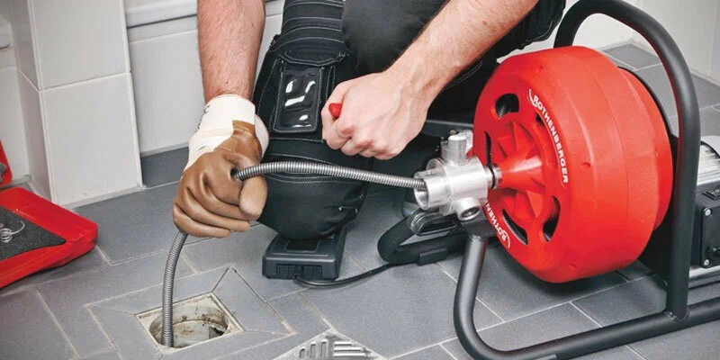 Plumber using a drain-cleaning machine in West Jordan