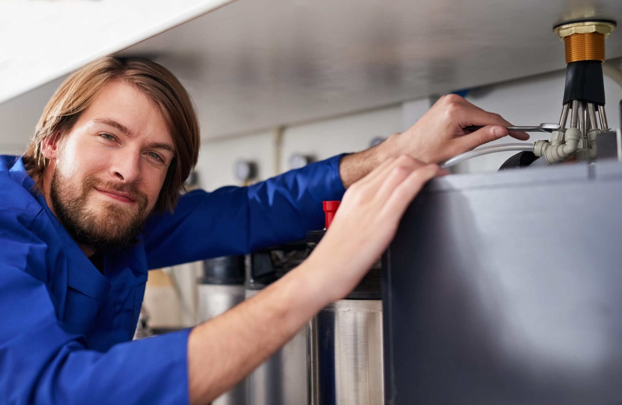 Technician servicing a residential water heater tank in West Jordan