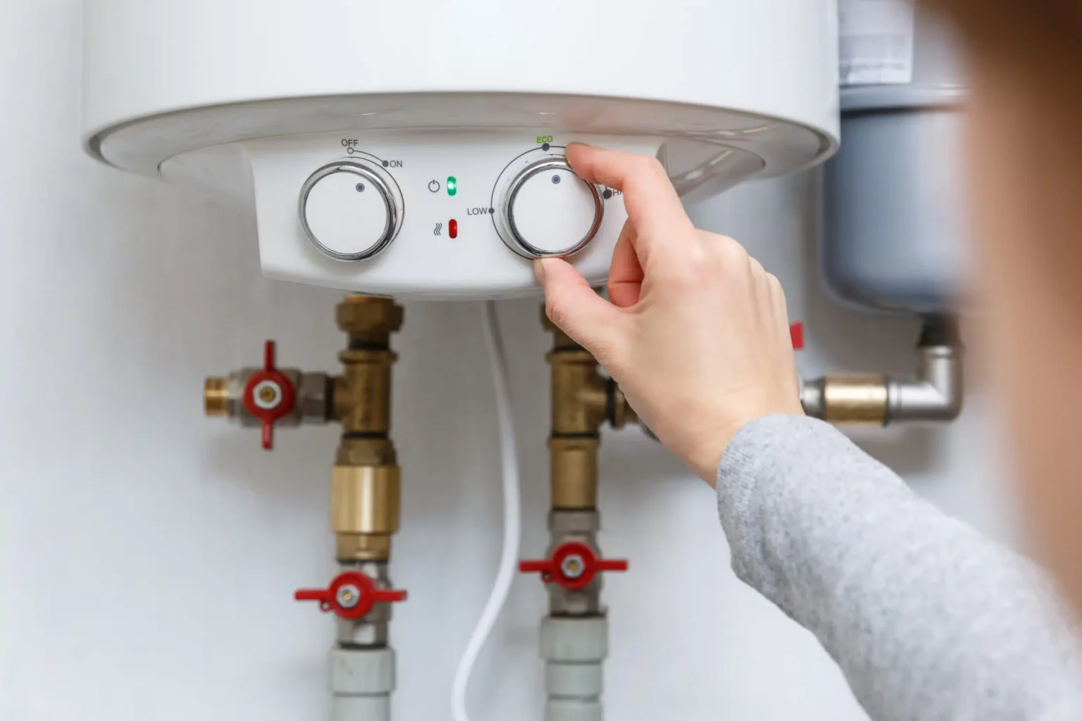 Homeowner adjusting the temperature controls on a water heater in West Jordan